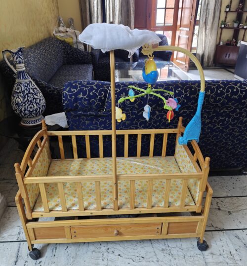 Wooden Baby cot with electronic toy and mosquito net.